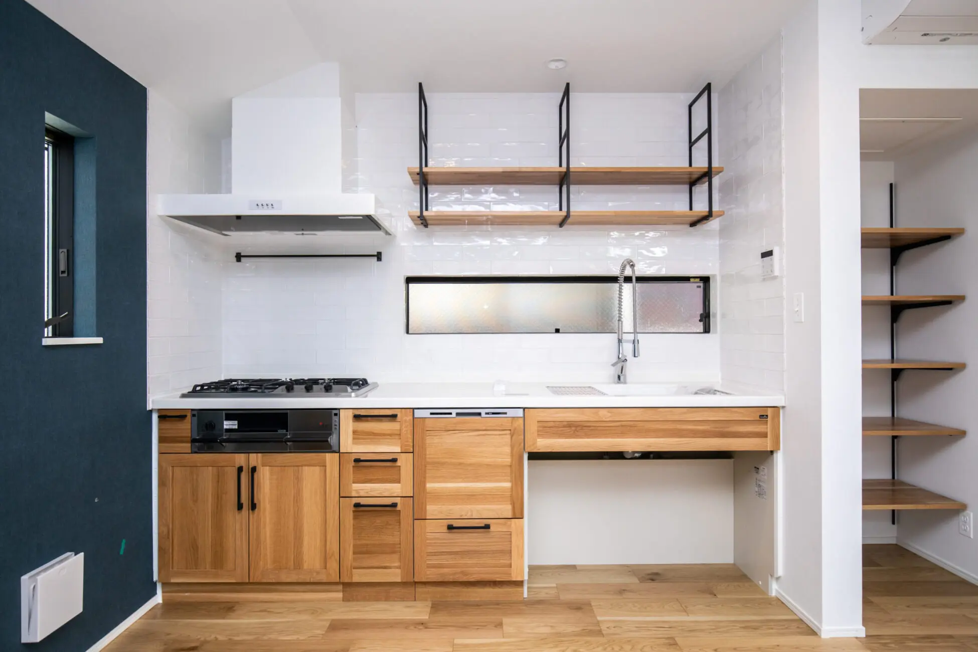 キッチンの壁面全体にタイルを施工。清潔感のあるキッチンとなっている。また、吊収納をアイアン調のものを採用した。