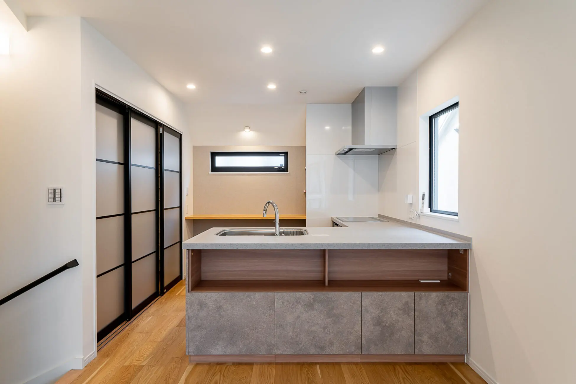 ダイング側を収納にしたL型キッチン。すぐ裏手には多目的カウンターを配置。