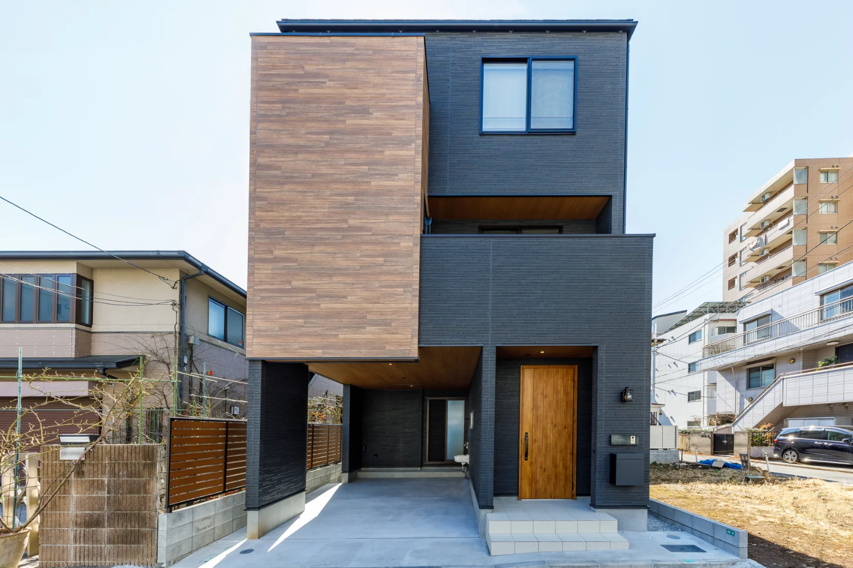 黒の外観にスクエアな木調のサイディングを使用