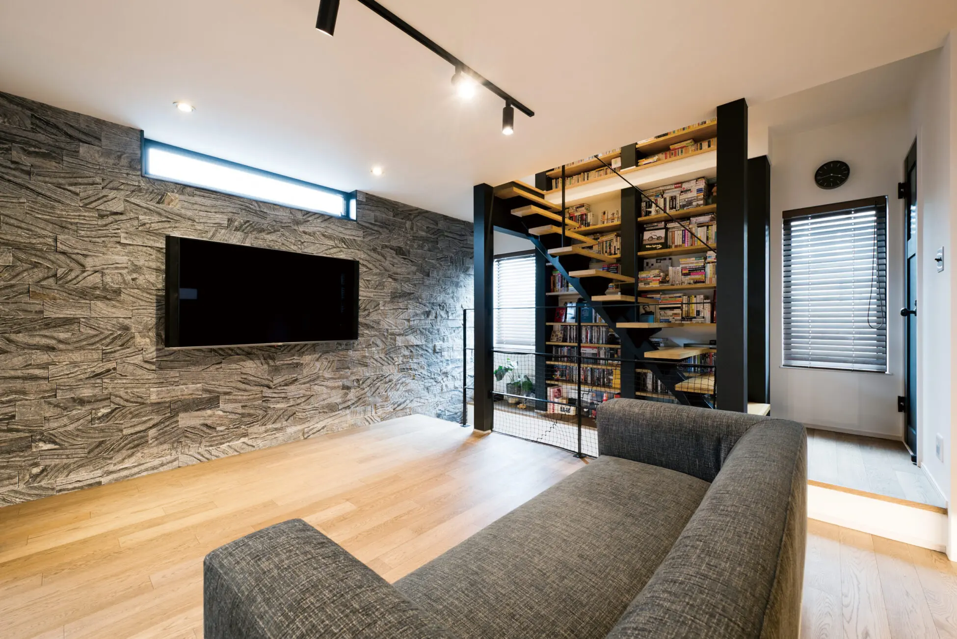 階段収納とリビング。TV裏のタイルは凹凸感のある重厚なものを採用